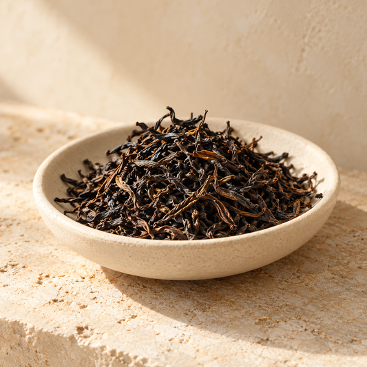 loose dark tea leaves in a shallow ivory dish