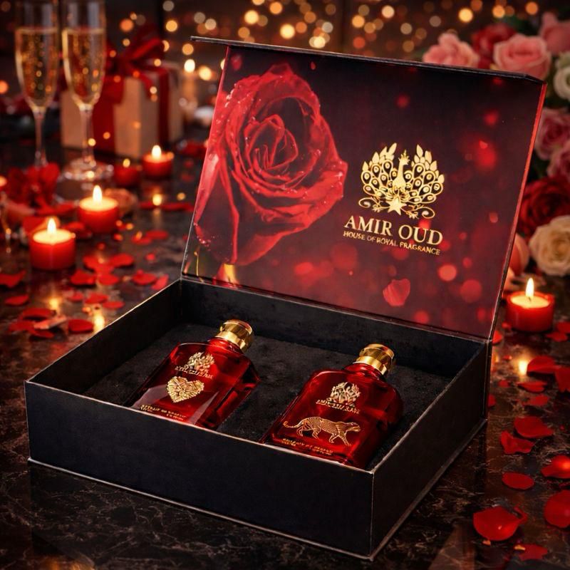 Two red perfume bottles in a decorative box with 'Amir Oud' branding, surrounded by candles and rose petals.