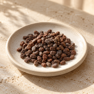 a small pile of amber-brown ambrette seeds on a pale ceramic dish