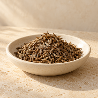 a small pile of curved caraway seeds in a shallow ivory dish