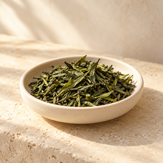 loose green tea leaves in a shallow ivory dish